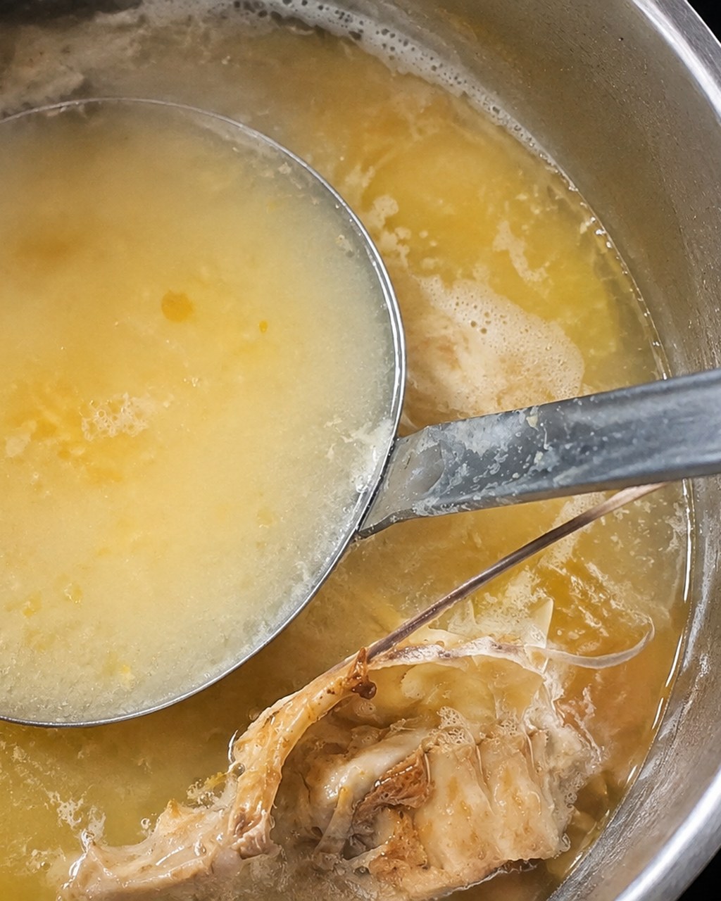 灰汁をとりながら煮込む鶏だし