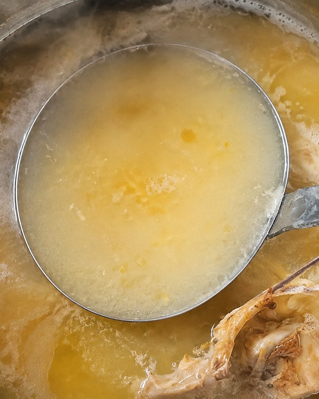 灰汁をとりながら煮込む鶏だし